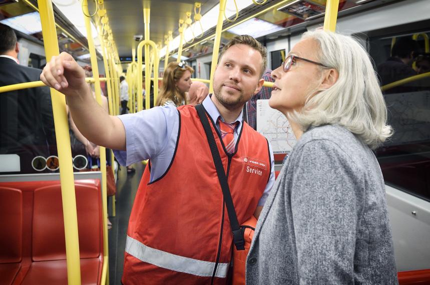 eine Frau mit grauen Haaren und ein Servicemitarbeiter in einem Ubahnzug