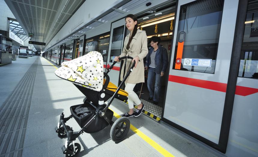 eine Frau mit Kinderwagen fährt aus einer U-Bahn auf den Bahnsteig