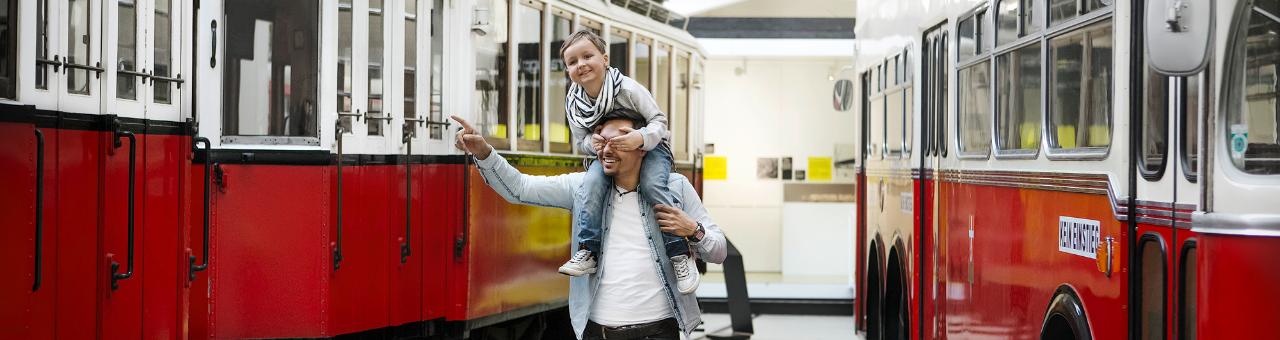 a man carries a child on his shoulders through the transport museum remise