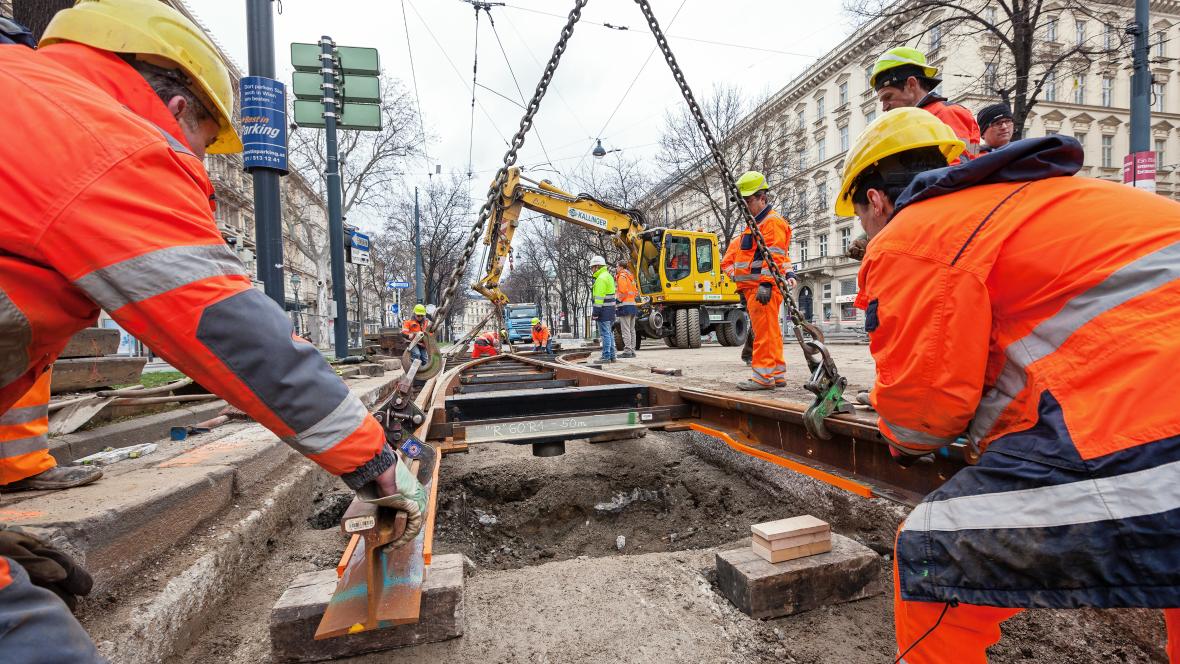 Gleisbauarbeiter legen neue Schienen mit einem Kran