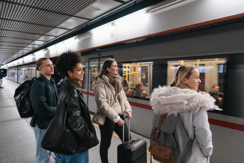 Eine Freundesgruppe steht am Bahnsteig und U-Bahn fährt ein