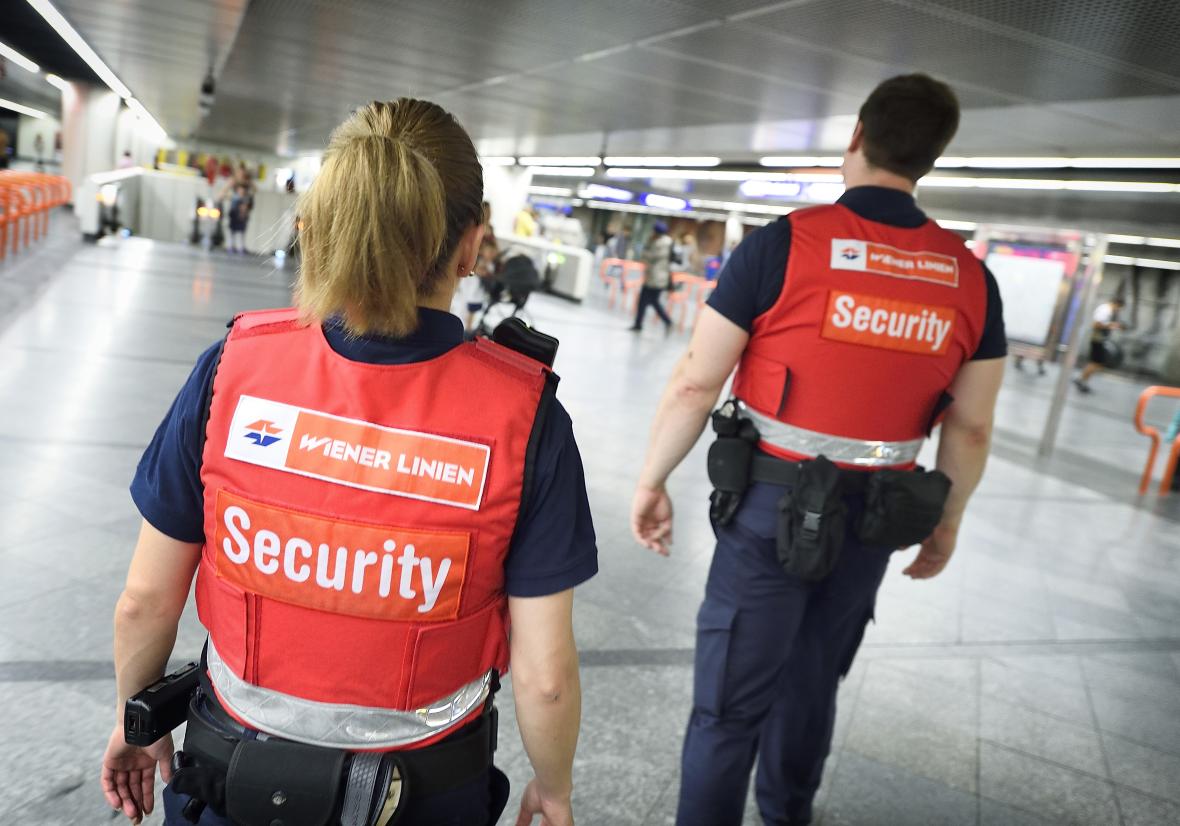zwei Personen in blauer Dienstkleidung und roten Schutzwesten mit der Aufschrift Security sind in der Ubahn unterwegs