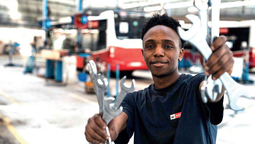 junger Mann in einer Werkstätte mit Schraubenschlüsseln in der Hand