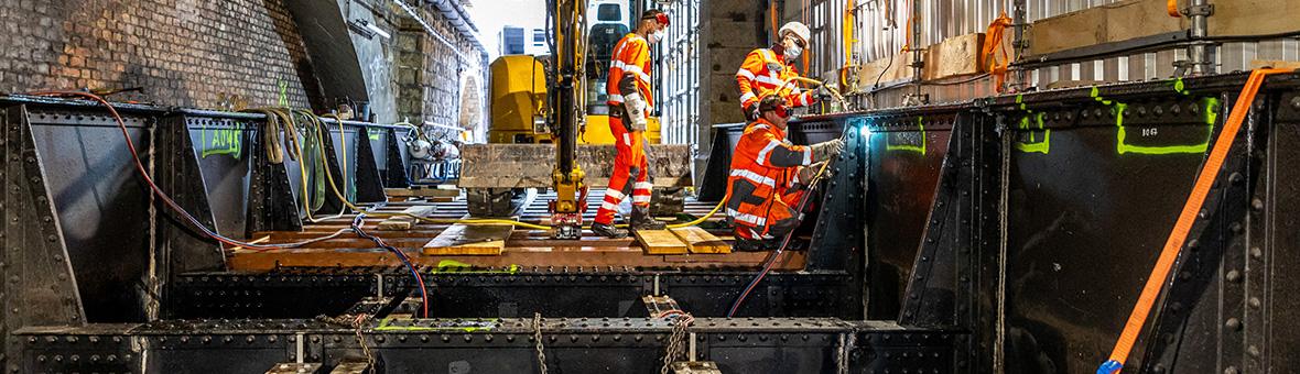 Arbeiter zerschneiden das alte Tragwerk aus Stahl