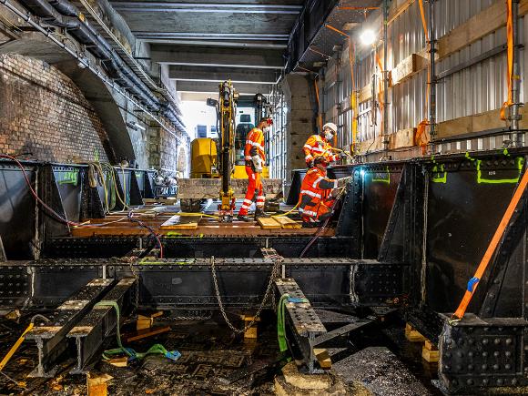 Bauarbeiter arbeiten mit Schweißgeräten an einer Stahlbrücke