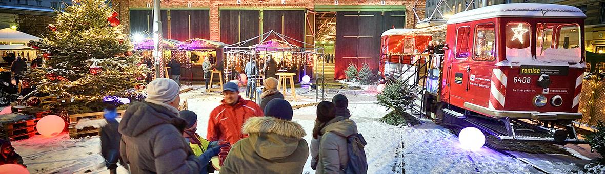 people standing between brick buildings at the Christmas market at the Remise transport museum