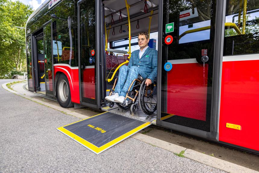 ein Rollstuhlfahrer fährt auf einer Rampe aus einem Bus