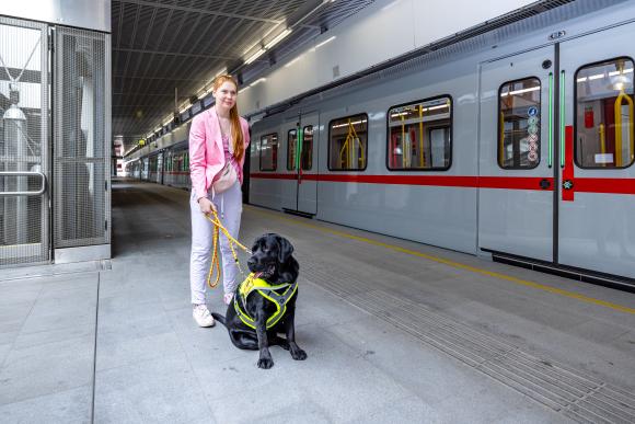 eine Frau mit Assistenzhund in einer U-Bahn-Station