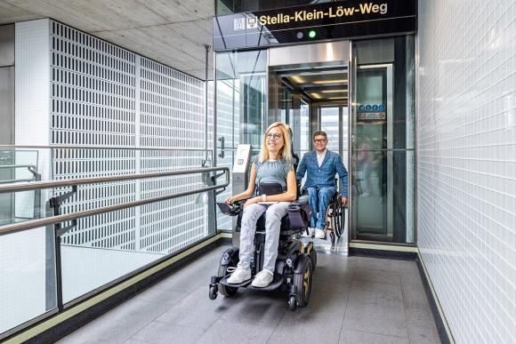 Ein Mann und eine Frau im Rollstuhl fahren aus dem Aufzug bei der U-Bahn-Station