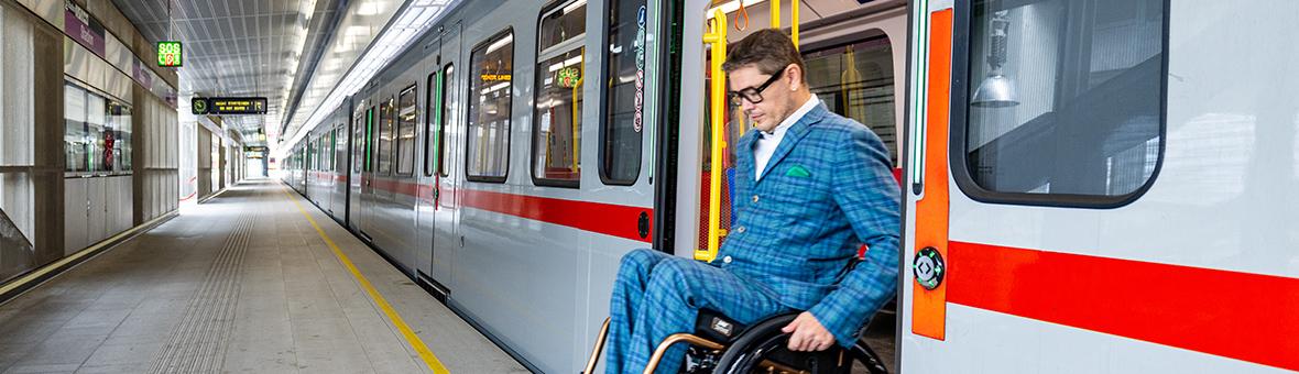 ein Rollstuhlfahrer fährt aus einer Ubahn auf den Bahnsteig