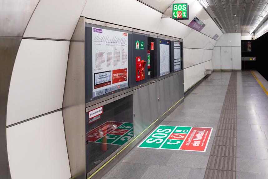 ein Ubahnsteig mit einem grünen SOS Zeichen und dem Zugnotstopp und der Notsprechstelle